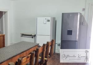 a kitchen with a refrigerator and a table at Steytlerville Karoo Backpackers in Steytlerville