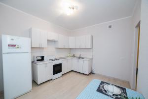 una cocina vacía con armarios blancos y nevera en Apartment on Khakima with Kremlin View, en Kazán