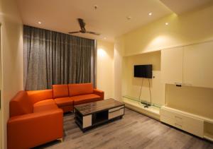 a living room with an orange couch and a tv at YAR INN CENTRAL in Vijayawāda