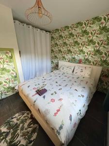 a bed in a bedroom with floral wallpaper at L'enjo'Leuze in Winée