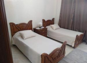 a room with two beds and a dresser and a bed sidx sidx at Apartment Centre Hamria in Meknès