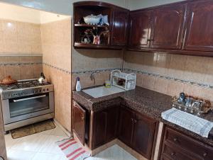 a kitchen with wooden cabinets and a sink and a stove at Apartment Centre Hamria in Meknès
