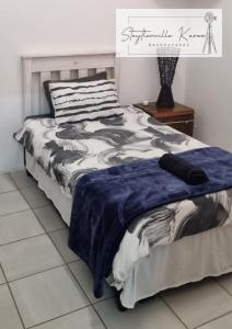 a bed with a blue and white comforter on it at Steytlerville Karoo Backpackers in Steytlerville