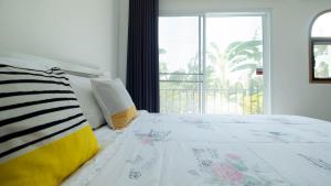 a bedroom with a white bed with a window at Baan Iris Salaya in Salaya