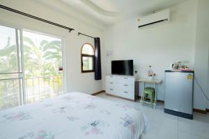 a bedroom with a bed and a tv and a window at Baan Iris Salaya in Salaya