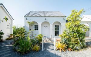 a white house with plants in front of it at Baan Iris Salaya in Salaya