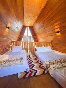 two beds in a room with wooden walls at Cabin Dieng Db in Diyeng