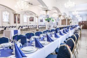 a row of tables and chairs in a room with chandeliers at Hotel Komfort Inn - Dwór Hubertus in Piekary Śląskie