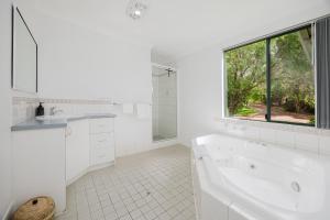 a white bathroom with a tub and a window at Surfside Ocean Beach Denmark Holiday Accommodation in Denmark +60 photos