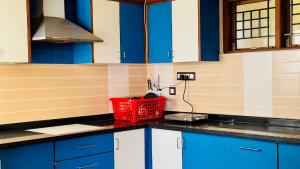 a kitchen with blue cabinets and a red basket on the counter at Hotel SK Temple View in Tiruvannāmalai +24 photos