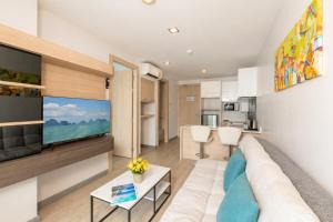 a living room with a couch and a flat screen tv at Kata Beach Pool View Condo - 400m from the Beach in Kata Beach +15 photos