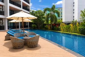 a swimming pool with chairs and an umbrella next to a building at Kata Beach Pool View Condo - 400m from the Beach in Kata Beach