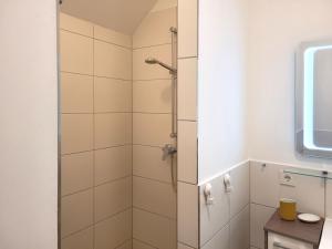 a shower in a bathroom with white tiles at Heiligenhafenbude 2 in Heiligenhafen +20 photos