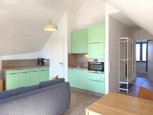 a living room with a couch and a kitchen with green cabinets at Heiligenhafenbude 2 in Heiligenhafen