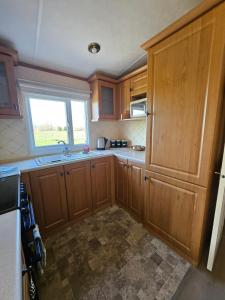 a kitchen with wooden cabinets and a window at Ruth's Repose Shropshire Country Retreat with private hot tub & Stunning Views in Shrewsbury
