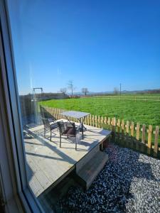 a table and bench on a deck with a view of a field at Ruth's Repose Shropshire Country Retreat with private hot tub & Stunning Views in Shrewsbury