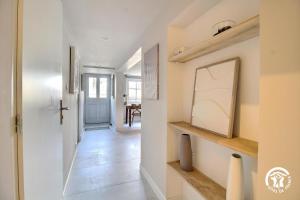 a hallway with white walls and a door with a picture at Le clos du figuier in Arzon