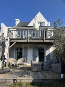 a house with a deck with chairs and a table at Le clos du figuier in Arzon