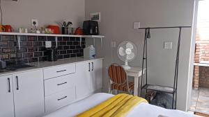 a kitchen with white cabinets and a table and a chair at 27 on Brunswick in Gqeberha