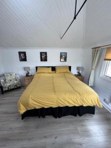 a bedroom with a large bed with a yellow bedspread at Woodland Chalet at Otters Green in Botley