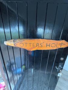 a wooden sign that says otters hut on a door at Woodland Chalet at Otters Green in Botley