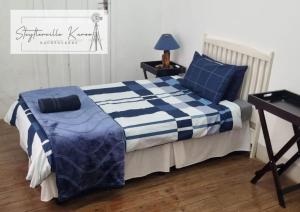 a bedroom with a bed with a blue and white comforter at Steytlerville Karoo Backpackers in Steytlerville +20 photos