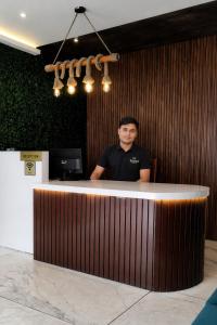 a man standing behind a wooden counter in a room at Teesta Hotels, Kalimpong in Kalimpong