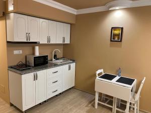a kitchen with white cabinets and a microwave and a table at Emanuela Home in Piatra Neamţ +6 photos