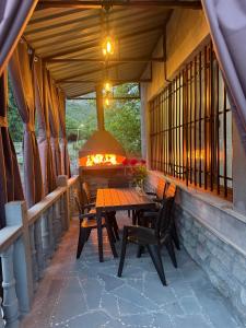 a porch with a table and chairs and a fireplace at Guest House MD 2 in Tatʼev