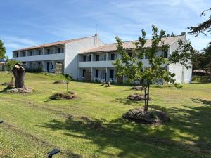 a building with trees in front of a yard at Hôtel des Dunes Noirmoutier in La Guérinière