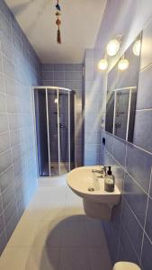 a blue tiled bathroom with a sink and a shower at Villa Henry in Grzybowo
