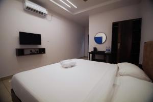 a bedroom with a white bed and a tv at Travlounge Adimali in Chillithodu +3 photos