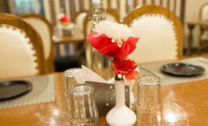 a wooden table with a vase with red flowers in it at Hotel Viva Palace By OPO Delhi Airport in New Delhi