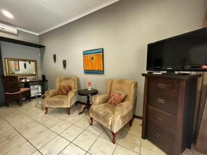 a living room with two chairs and a flat screen tv at Abangane Guest Lodge in Hazyview