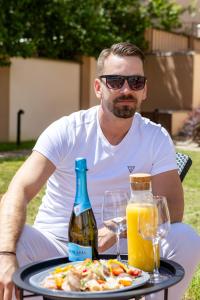 a man sitting at a table with a plate of food and a bottle at Karos Bianco Apartmanház in Zalakaros
