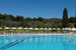a large swimming pool with white umbrellas and chairs at Hydra Beach Resort in Thermisía