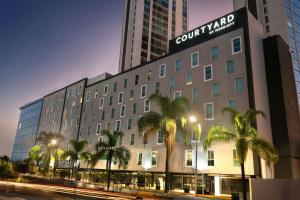 a hotel with palm trees in front of a building at Courtyard by Marriott Guadalajara Andares in Zapopan