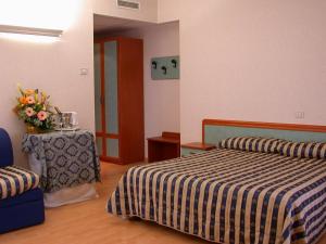 a bedroom with two beds and a table with a vase of flowers at Hotel La Pergola in Rionero in Vulture