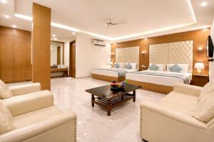 a hotel room with two beds and a coffee table at Hotel Viva Palace By OPO Delhi Airport in New Delhi