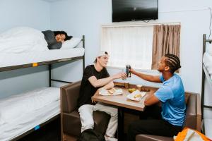 two men sitting at a table in a room with bunk beds at Rotterdam Teleport Hostel in Rotterdam