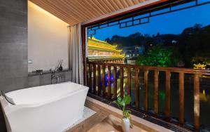 a bathroom with a tub and a balcony with a view at Phoenix River View Hotel-Free pick up service from Railway in Fenghuang County +57 photos