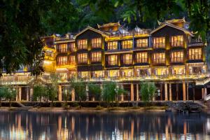 a large building with a pond in front of it at Phoenix River View Hotel-Free pick up service from Railway in Fenghuang County