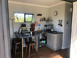 a kitchen with a counter and a table with a microwave at Plett Pods - Casetta del Fuoco - Eco Container Cottage in Plettenberg Bay