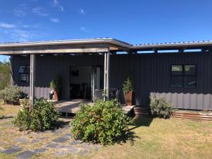 a black house with a porch and some bushes at Plett Pods - Casetta del Fuoco - Eco Container Cottage in Plettenberg Bay