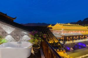 a bath tub on a balcony next to a building at Phoenix River View Hotel-Free pick up service from Railway in Fenghuang County