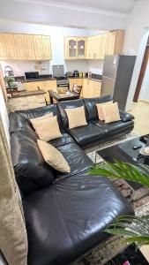 a living room with two black leather couches and a kitchen at Vine Vale in Kampala