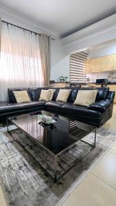 a living room with a black couch and a glass table at Vine Vale in Kampala