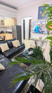a living room with a black leather couch and a tv at Vine Vale in Kampala