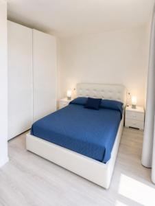 ein weißes Schlafzimmer mit einem Bett mit blauer Bettwäsche in der Unterkunft Mare Incanto - Agenzia Cocal in Caorle