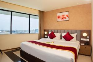 a hotel room with a large bed with red pillows at Ascot Hotel in Kozhikode
